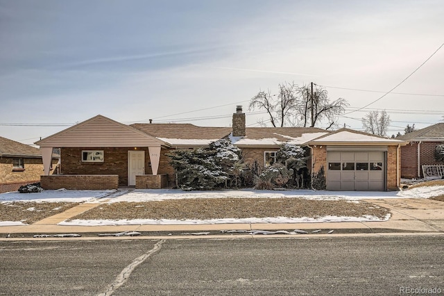 view of front of property with a garage, driveway, a chimney, and brick siding