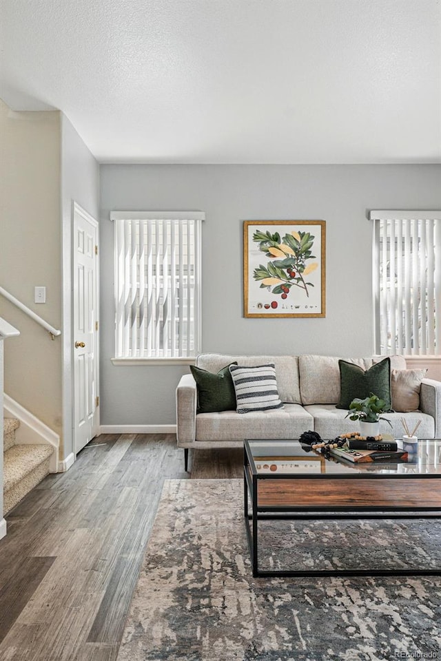living area featuring baseboards, stairway, and wood finished floors