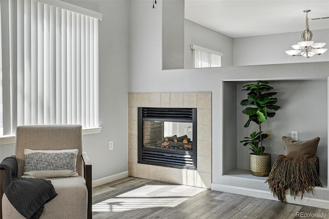 living area featuring a wealth of natural light, a chandelier, wood finished floors, and visible vents