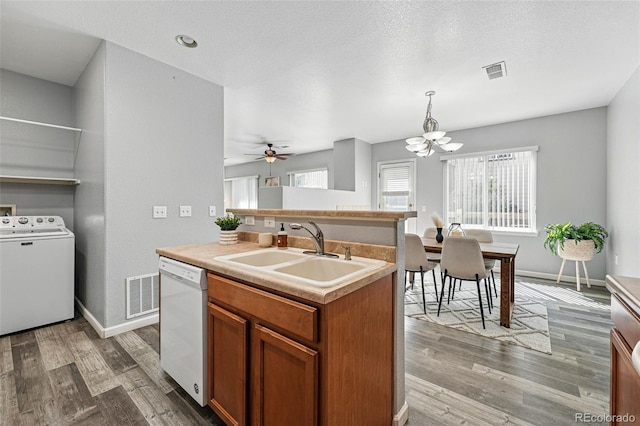 kitchen with a sink, white dishwasher, washer / dryer, and visible vents