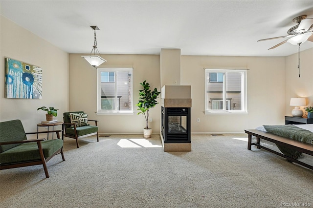 carpeted living area with visible vents, a fireplace, baseboards, and ceiling fan