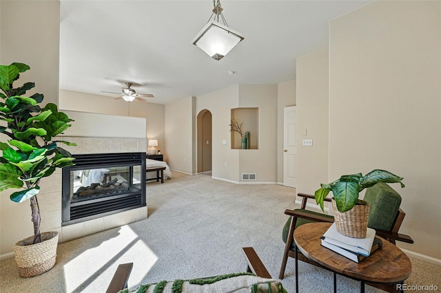 living room featuring baseboards, ceiling fan, visible vents, arched walkways, and light colored carpet