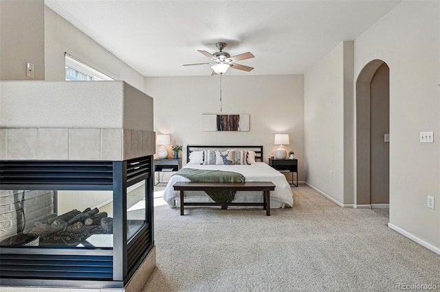 bedroom with baseboards, a ceiling fan, carpet, and arched walkways