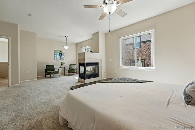 carpeted bedroom featuring baseboards, multiple windows, and a tile fireplace