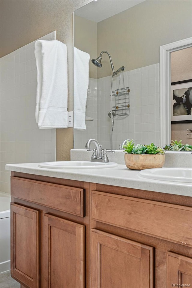 full bath featuring a sink, double vanity, tiled shower, and a bathtub