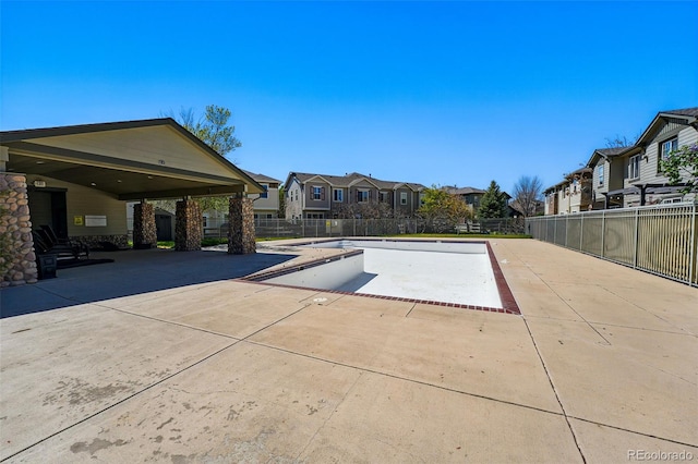 view of pool with a patio, fence, and a residential view