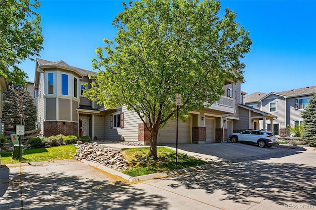 view of front facade with driveway, a residential view, brick siding, and an attached garage