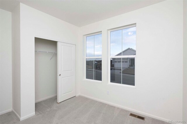 unfurnished bedroom featuring light carpet and a closet