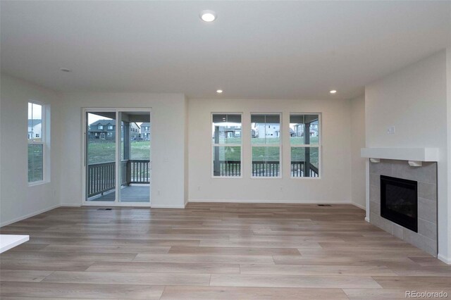 unfurnished living room with light hardwood / wood-style flooring, a fireplace, and a healthy amount of sunlight