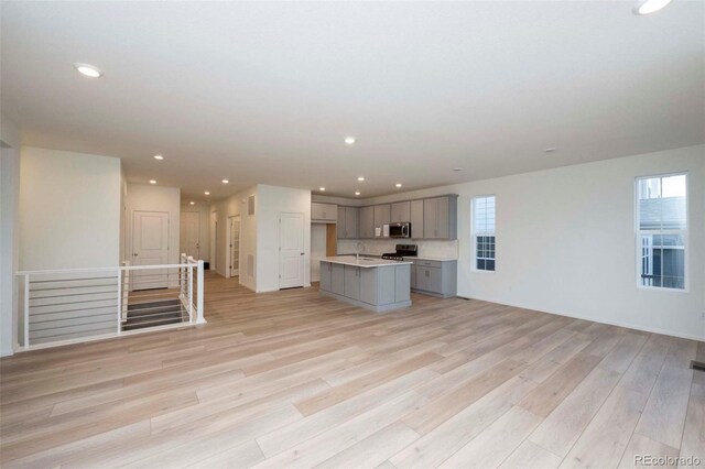 unfurnished living room featuring sink and light hardwood / wood-style flooring