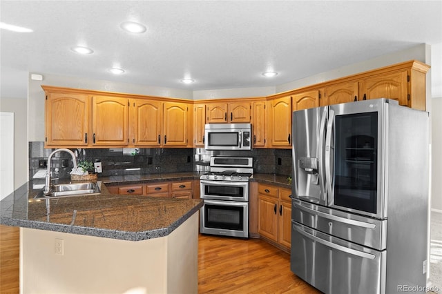 kitchen featuring backsplash, sink, stainless steel appliances, and light wood-type flooring