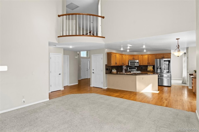 kitchen with stainless steel appliances, tasteful backsplash, kitchen peninsula, pendant lighting, and light carpet