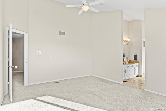 carpeted empty room featuring ceiling fan and a high ceiling