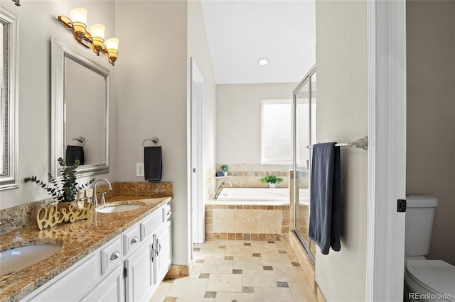 bathroom featuring vanity, a relaxing tiled tub, and toilet