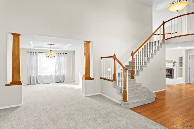 stairway with decorative columns, carpet floors, and a tray ceiling