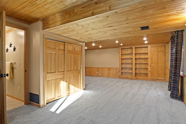 interior space with light colored carpet, crown molding, wooden walls, and wood ceiling