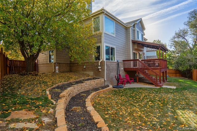 rear view of property featuring a lawn, a patio area, and a wooden deck