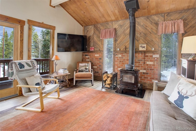 living room with light hardwood / wood-style floors, a wood stove, wood ceiling, and wood walls