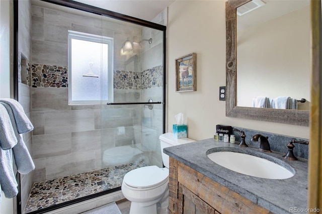 bathroom with vanity, a shower with shower door, and toilet