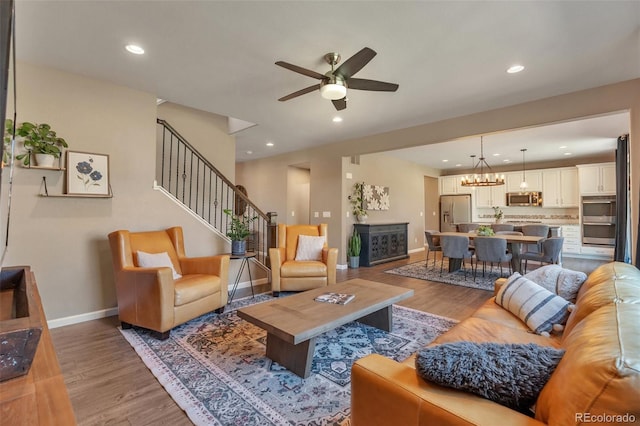 living area featuring ceiling fan, wood finished floors, baseboards, recessed lighting, and stairs