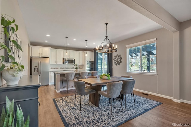 dining area featuring wood finished floors, a chandelier, recessed lighting, and baseboards