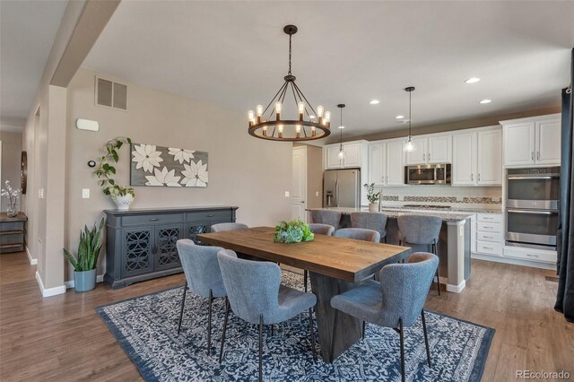 dining space with light wood-style flooring, a chandelier, baseboards, and recessed lighting