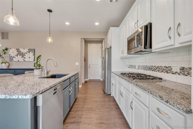 kitchen with appliances with stainless steel finishes, a sink, white cabinetry, light wood-style floors, and recessed lighting