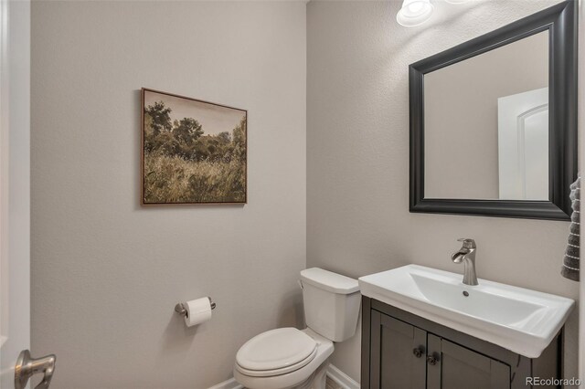 bathroom with toilet, baseboards, and vanity