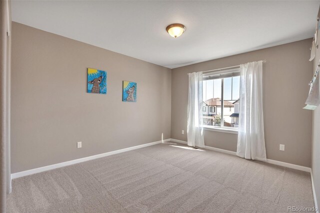 carpeted spare room featuring baseboards