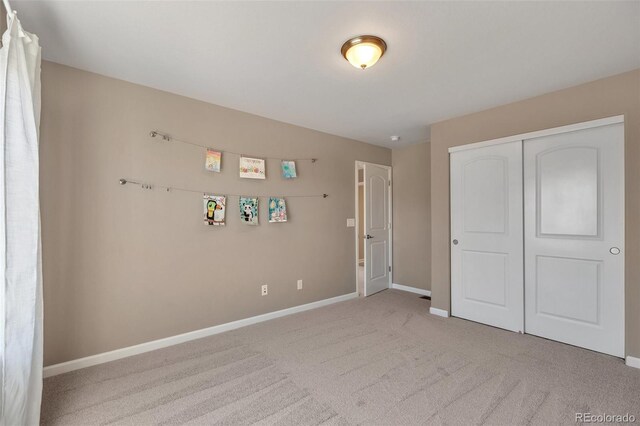 unfurnished bedroom with carpet flooring, baseboards, and a closet