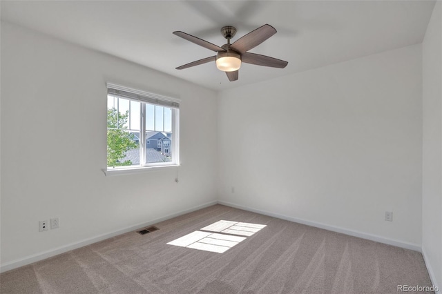 spare room with carpet, a ceiling fan, and baseboards