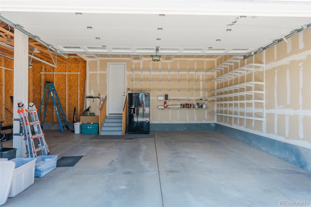 garage featuring black refrigerator with ice dispenser