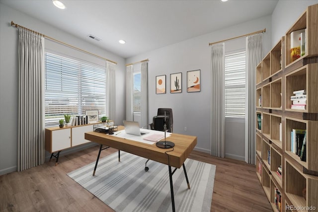 office featuring baseboards, visible vents, a wealth of natural light, and wood finished floors