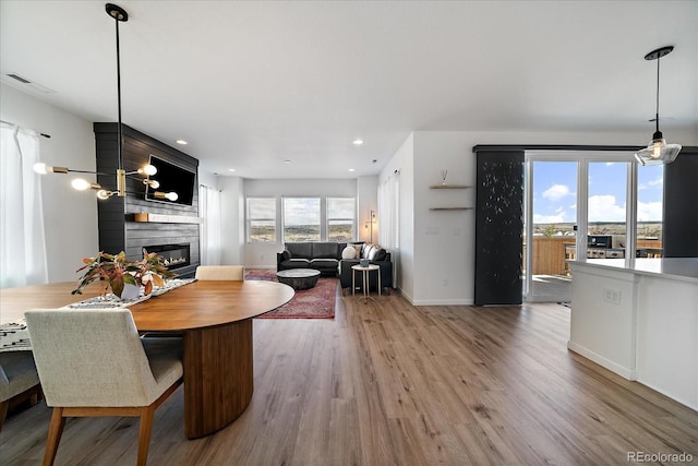 dining space with visible vents, wood finished floors, baseboards, recessed lighting, and a large fireplace