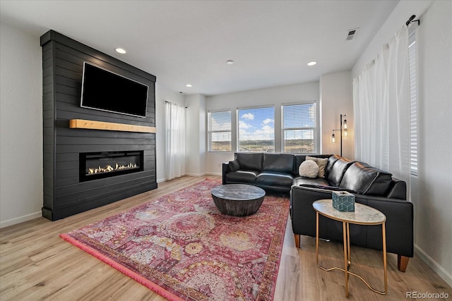living room with baseboards, a fireplace, wood finished floors, and visible vents