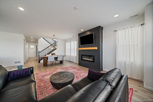 living room featuring stairs, baseboards, visible vents, and light wood-style flooring