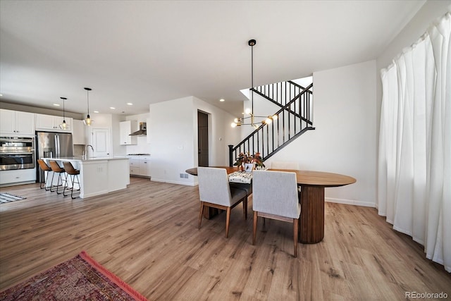 dining room with recessed lighting, light wood-style flooring, stairs, and baseboards