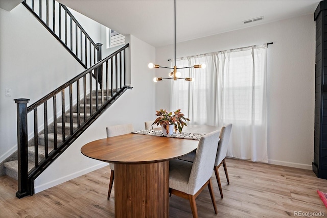 dining room featuring visible vents, baseboards, light wood finished floors, and stairs