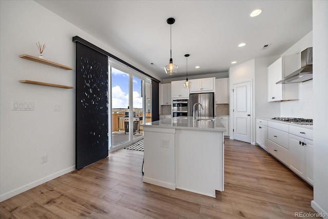 kitchen featuring light countertops, wall chimney exhaust hood, white cabinetry, tasteful backsplash, and appliances with stainless steel finishes