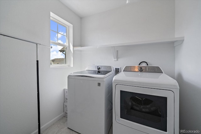 laundry room with laundry area, baseboards, light tile patterned flooring, and washing machine and clothes dryer