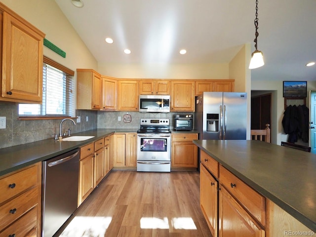 kitchen with appliances with stainless steel finishes, light hardwood / wood-style floors, sink, lofted ceiling, and tasteful backsplash