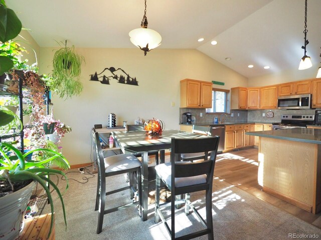 dining room featuring light wood-type flooring, sink, and vaulted ceiling