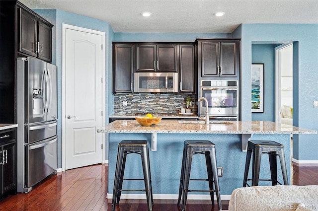 7426 E 148th Pl, Thornton, CO 80602 - kitchen featuring stainless steel appliances, decorative backsplash, light stone counters, and dark wood-style flooring