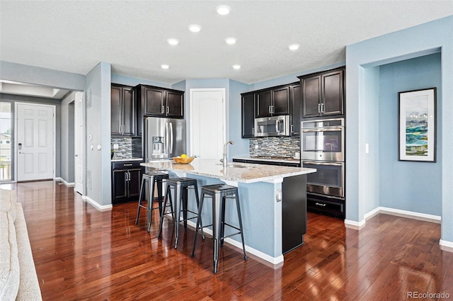 7426 E 148th Pl, Thornton, CO 80602 - kitchen featuring stainless steel appliances, a sink, a kitchen breakfast bar, backsplash, and an island with sink