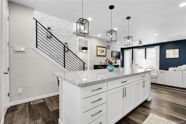 kitchen featuring visible vents, open floor plan, dark wood-style floors, white cabinets, and light stone counters