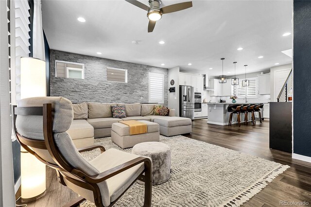 living room featuring a ceiling fan, recessed lighting, plenty of natural light, and dark wood-type flooring