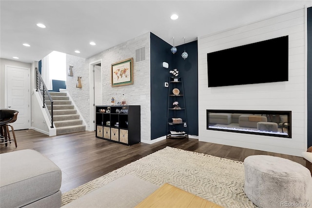 living area with a fireplace, stairs, wood finished floors, and visible vents