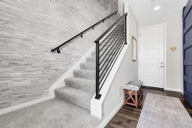 stairway featuring track lighting, baseboards, wood finished floors, and visible vents