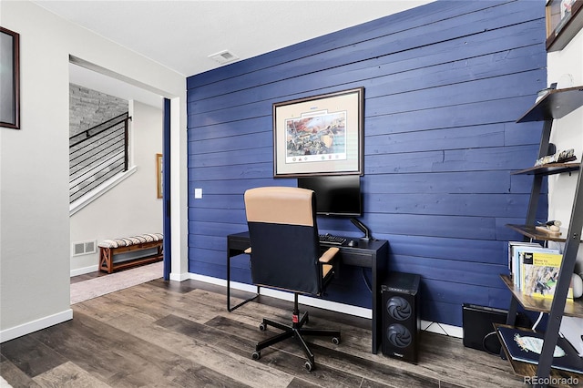 office with wood walls, visible vents, baseboards, and wood finished floors