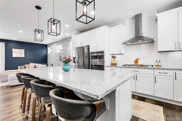 kitchen with a center island, stainless steel appliances, recessed lighting, and wall chimney exhaust hood